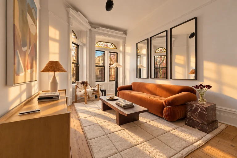 Angled living-room view with an orange sofa, wood coffee table and marble side table at 731 Putnam