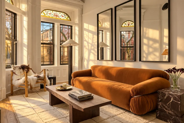Orange sofa and wood coffee table beside stained-glass windows at 731 Putnam