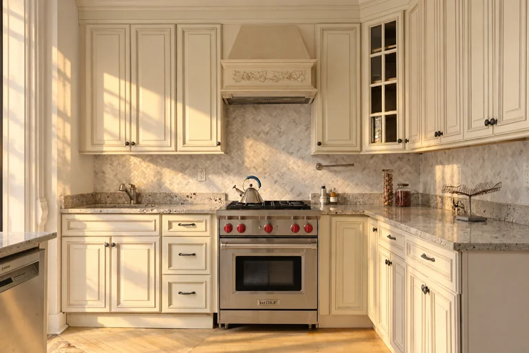 Cream kitchen cabinetry and stainless steel range in golden-hour light at 731 Putnam