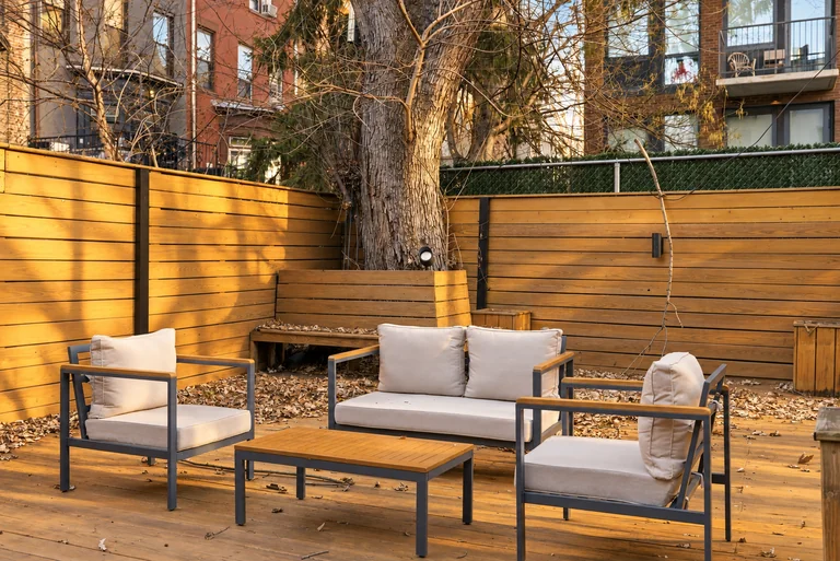 Wood-fenced patio seating around a low table beneath a bare tree at 731 Putnam