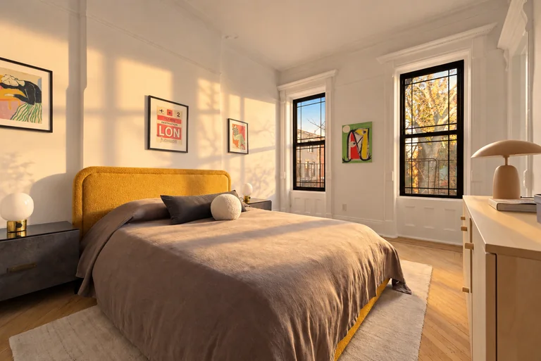 Golden-hour view of the mustard bed, gray linens, framed art and white dresser.