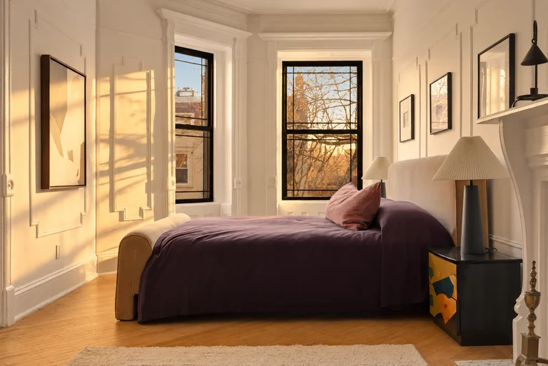 Purple-covered bed beside tall windows and a patterned bedside table at 731 Putnam