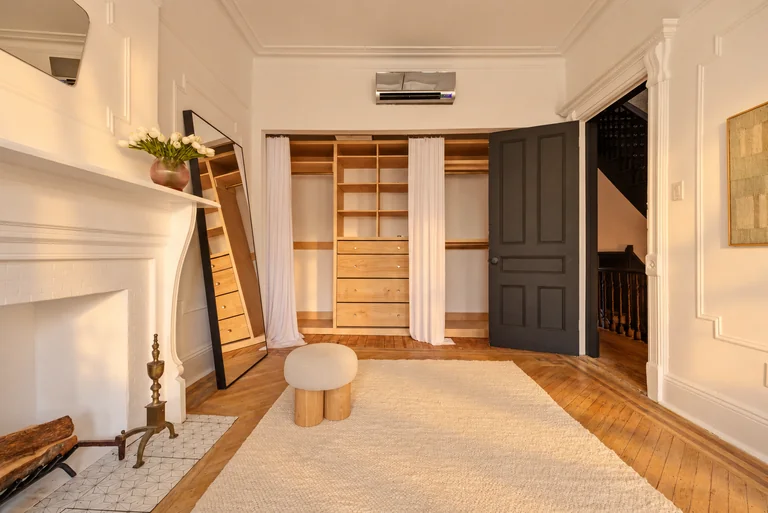 Bedroom dressing area with an open wood wardrobe, floor mirror and dark doorway at 731 Putnam