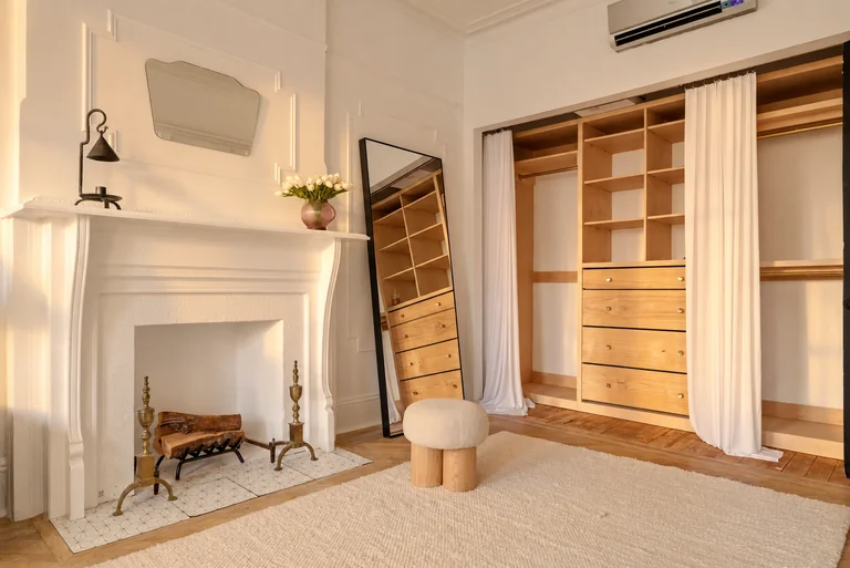White fireplace beside the open wood wardrobe and floor mirror at 731 Putnam