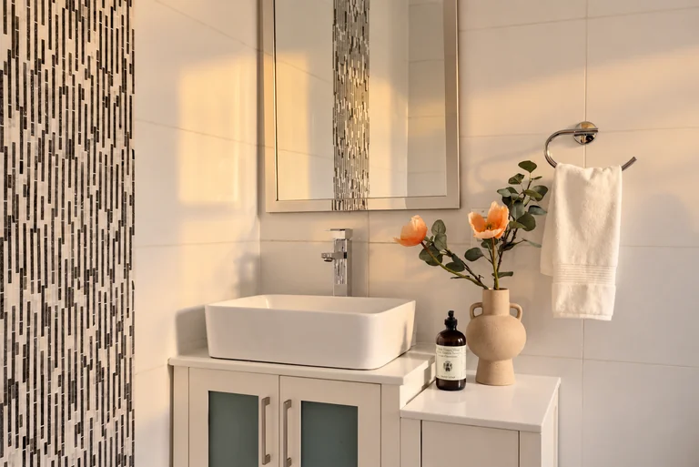 Bathroom vanity with a vessel sink, mosaic tile, peach flowers and white towel at 731 Putnam