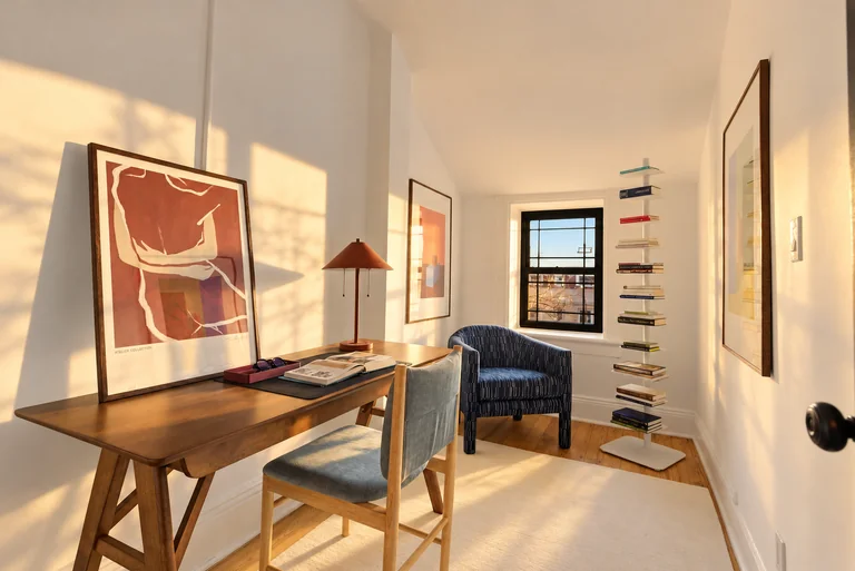 Home office with a wood desk, blue chairs and a freestanding book tower at 731 Putnam